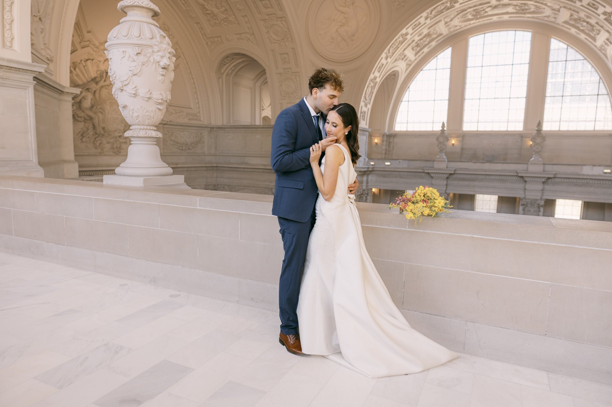 Bride and groom holding each other with grand background view inside San Francisco City Hall