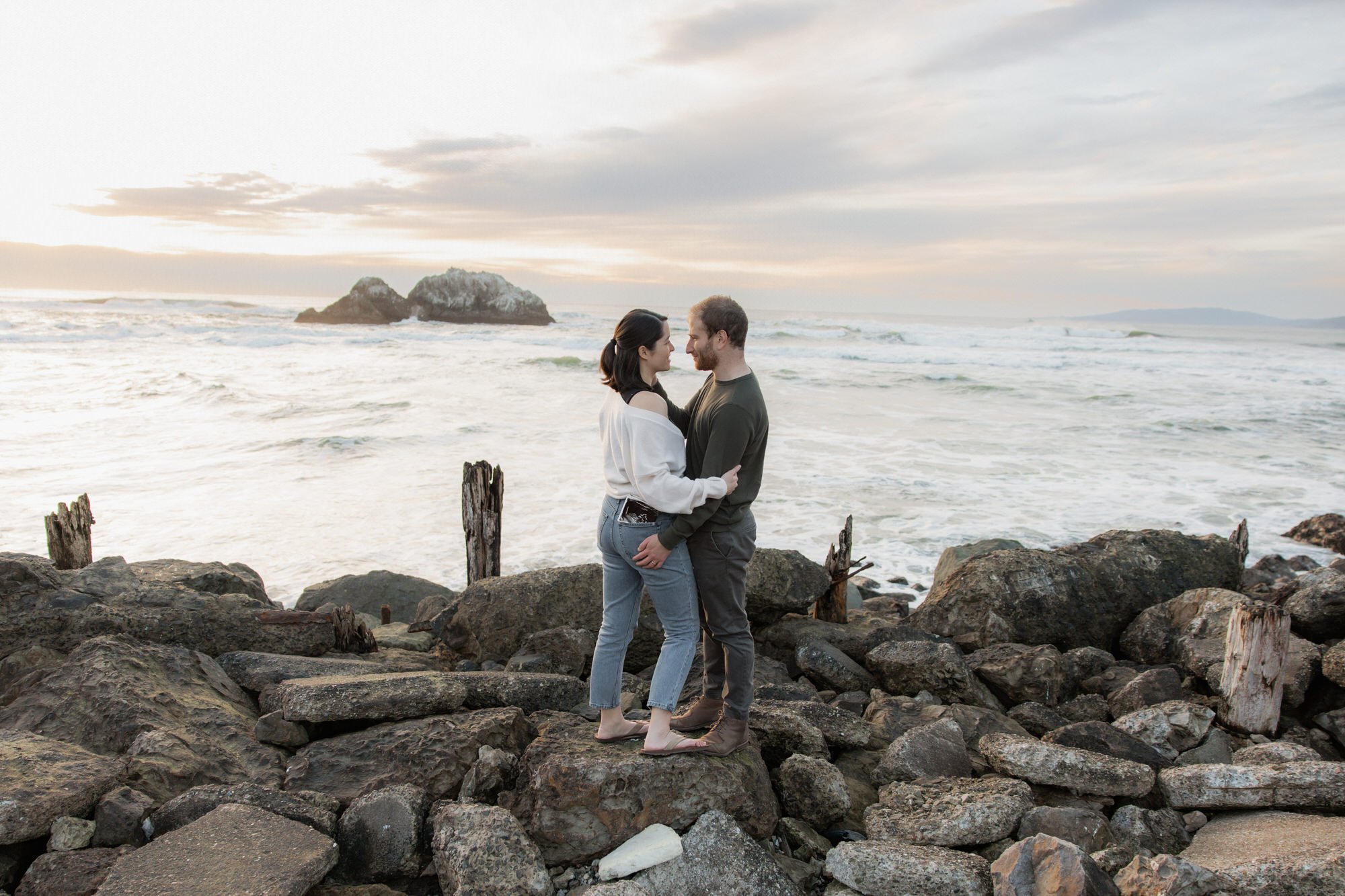 Parents to be holding each other at Sutro Baths for baby announcement photos